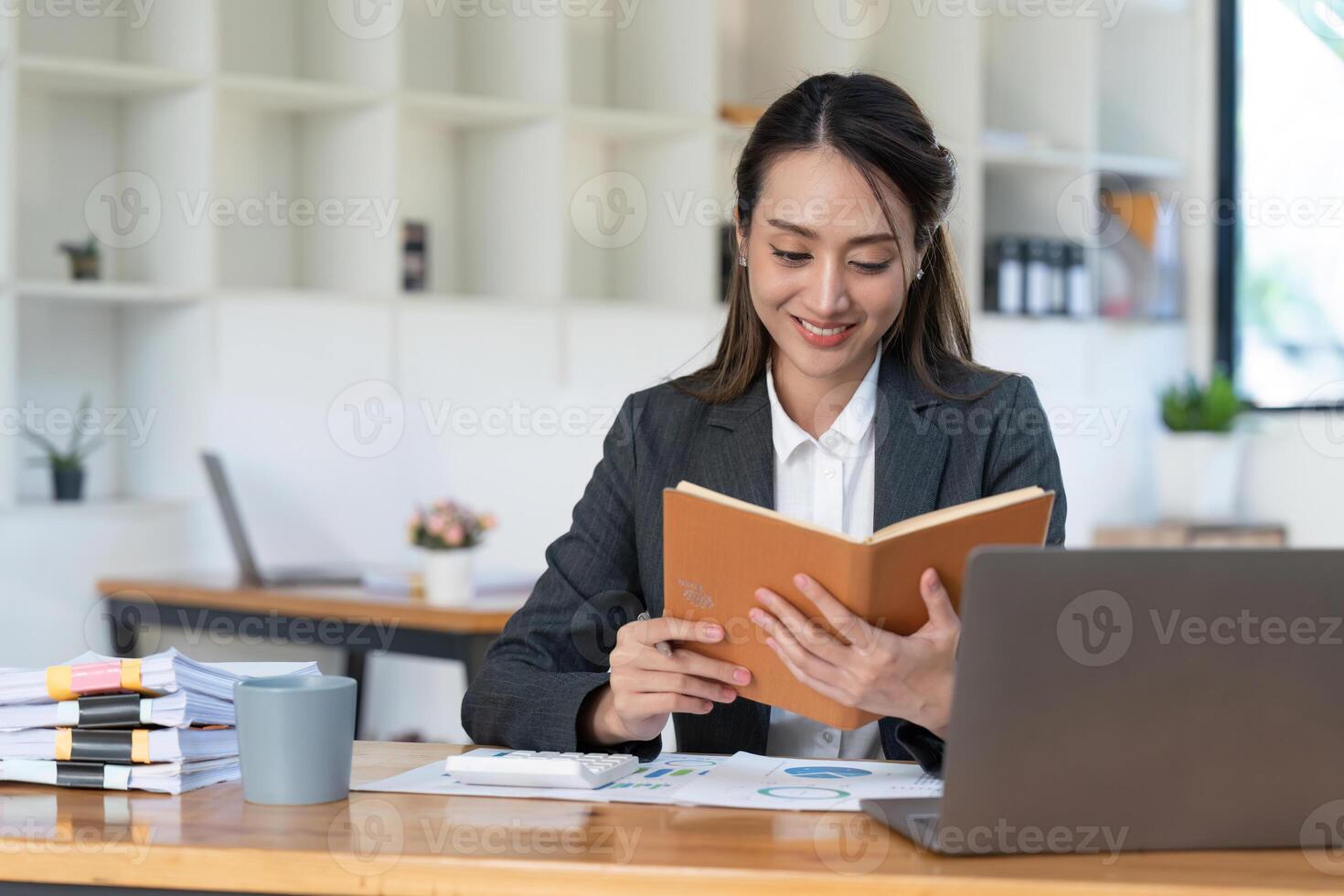 Smiling Young Asian Business women working with calculator, business document and laptop computer notebook, financial inspector and secretary making report,Internal Revenue Service checking document. photo