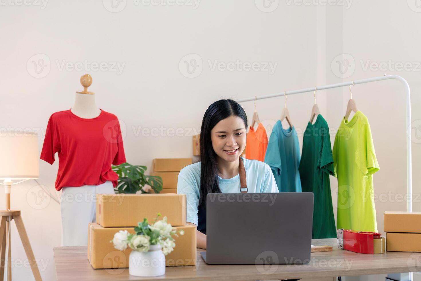 Young successful asian woman doing clothing business by open shop and selling online. she using laptop computer. online sell marketing delivery, SME e-commerce telemarketing concept photo
