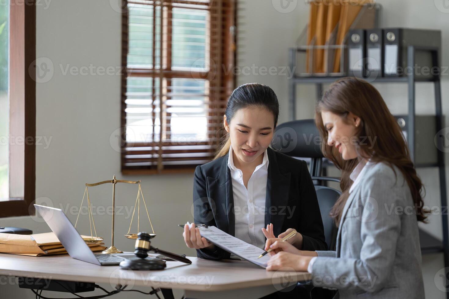 Female lawyer discuss to a legal document explaining the terms of a consultation with a businesswoman. before signing a contract with a law firm. photo