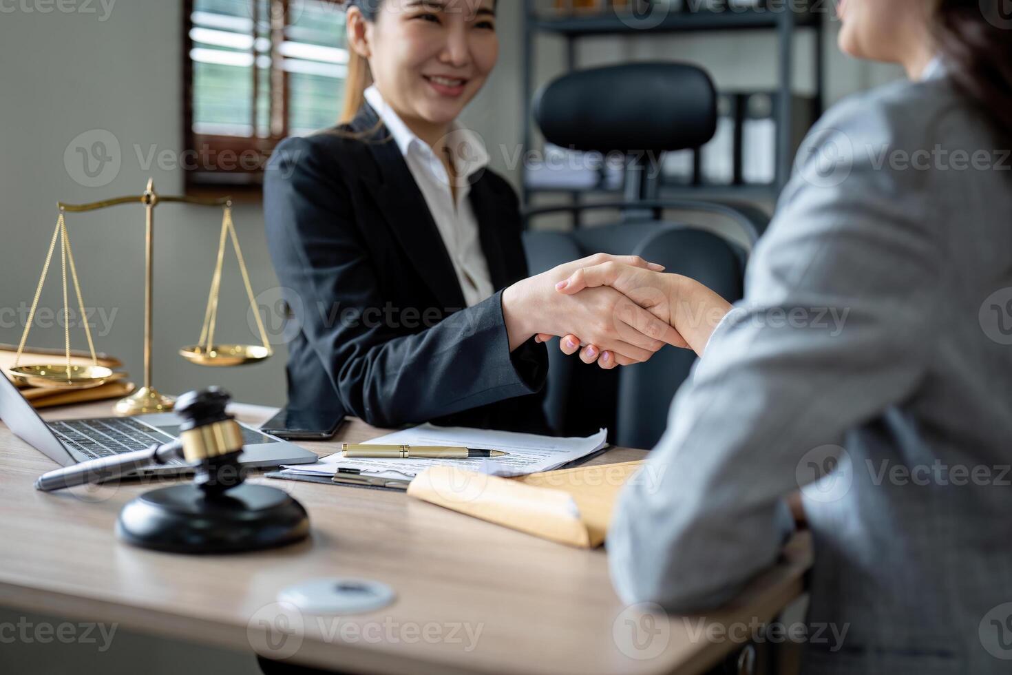 Gavel Justice hammer on wooden table with judge and client shaking hands after adviced in background at courtroom, lawyer service concept. photo