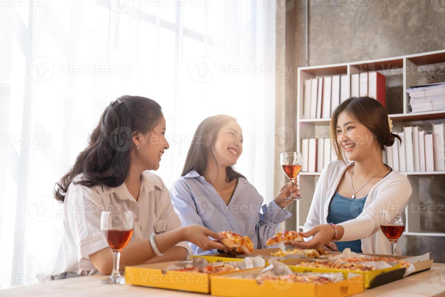Group of Asian friends gather to celebrate Christmas with champagne and eating pizza at home. Joy of holiday party with friends or colleague concept photo