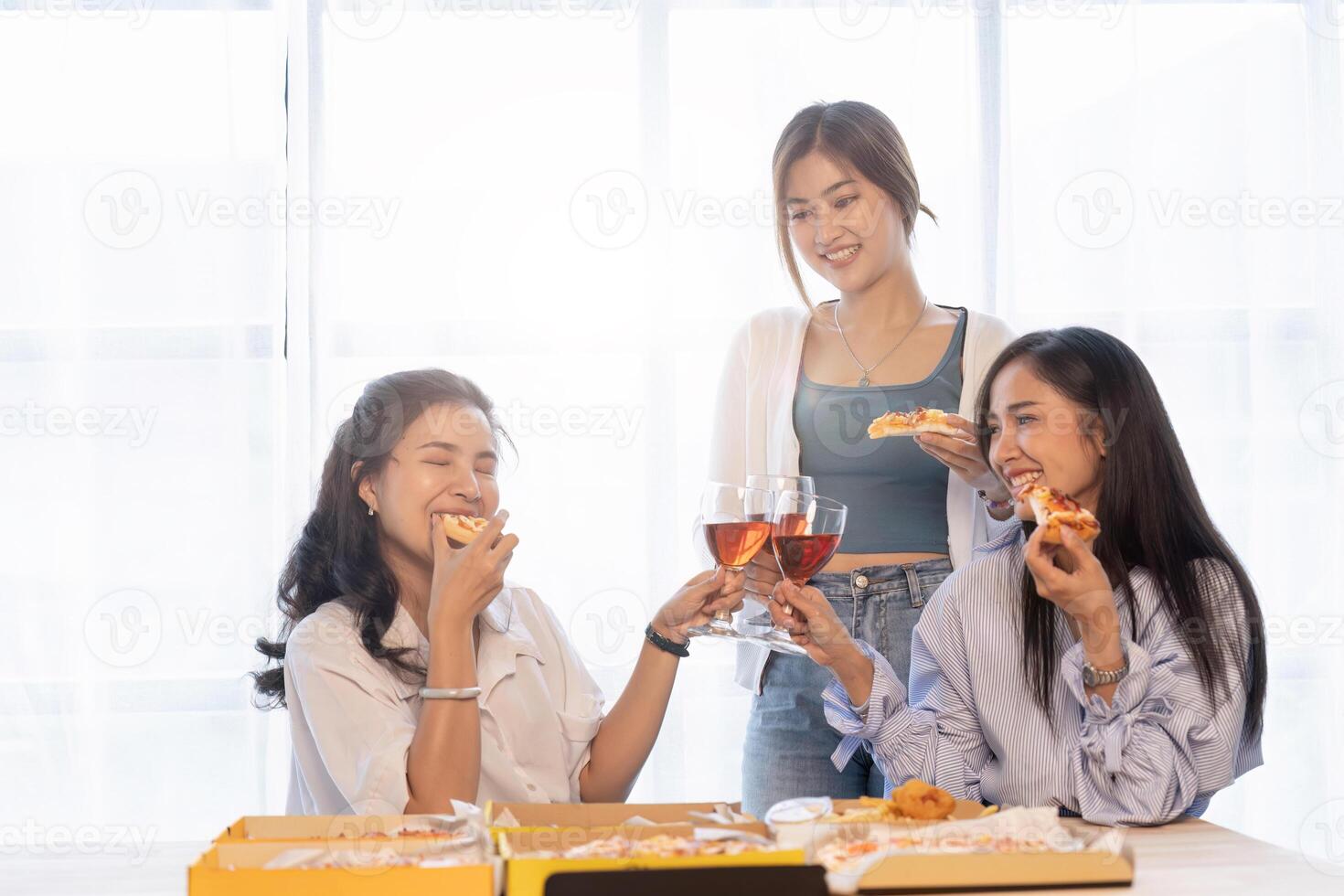 Group of Asian friends gather to celebrate Christmas with champagne and eating pizza at home. Joy of holiday party with friends or colleague concept photo