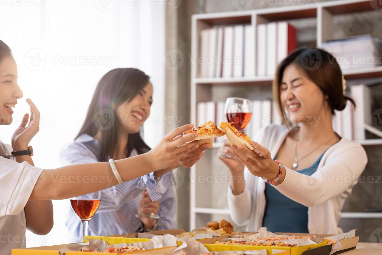 Group of Asian friends gather to celebrate Christmas with champagne and eating pizza at home. Joy of holiday party with friends or colleague concept photo