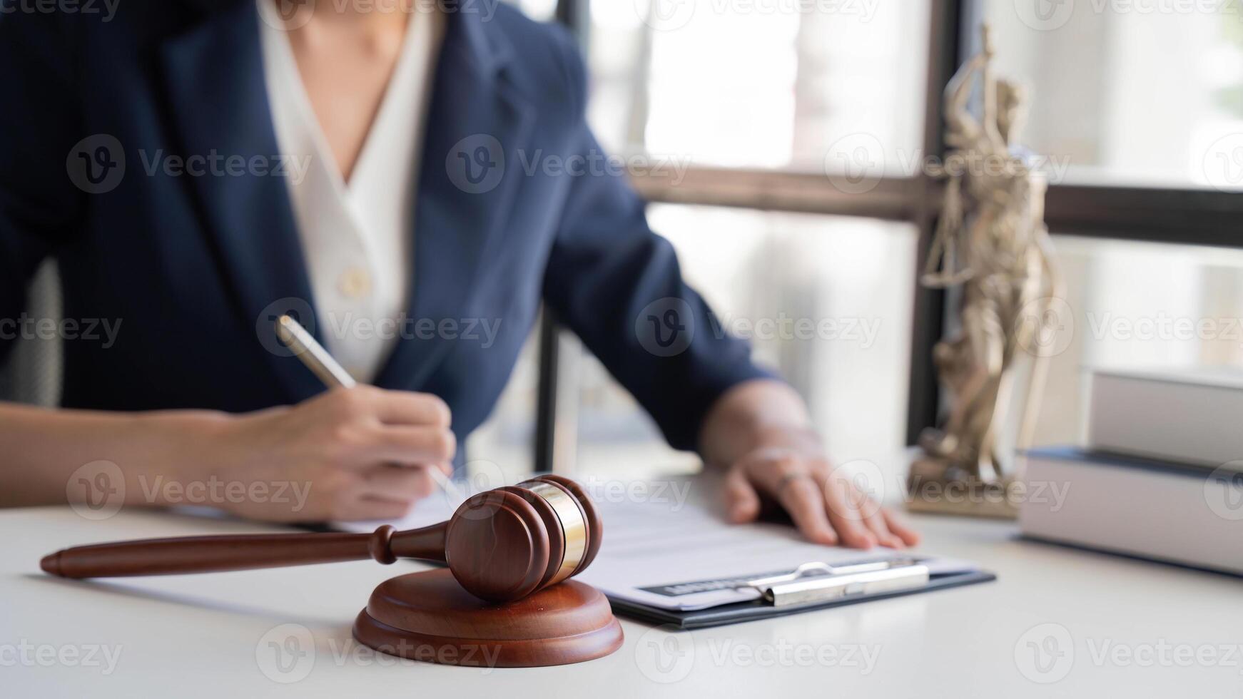 Asian female lawyer or legal advisor working with scales of justice Sitting at her desk holding a book on the scale of jurisprudence concepts to study and find information photo