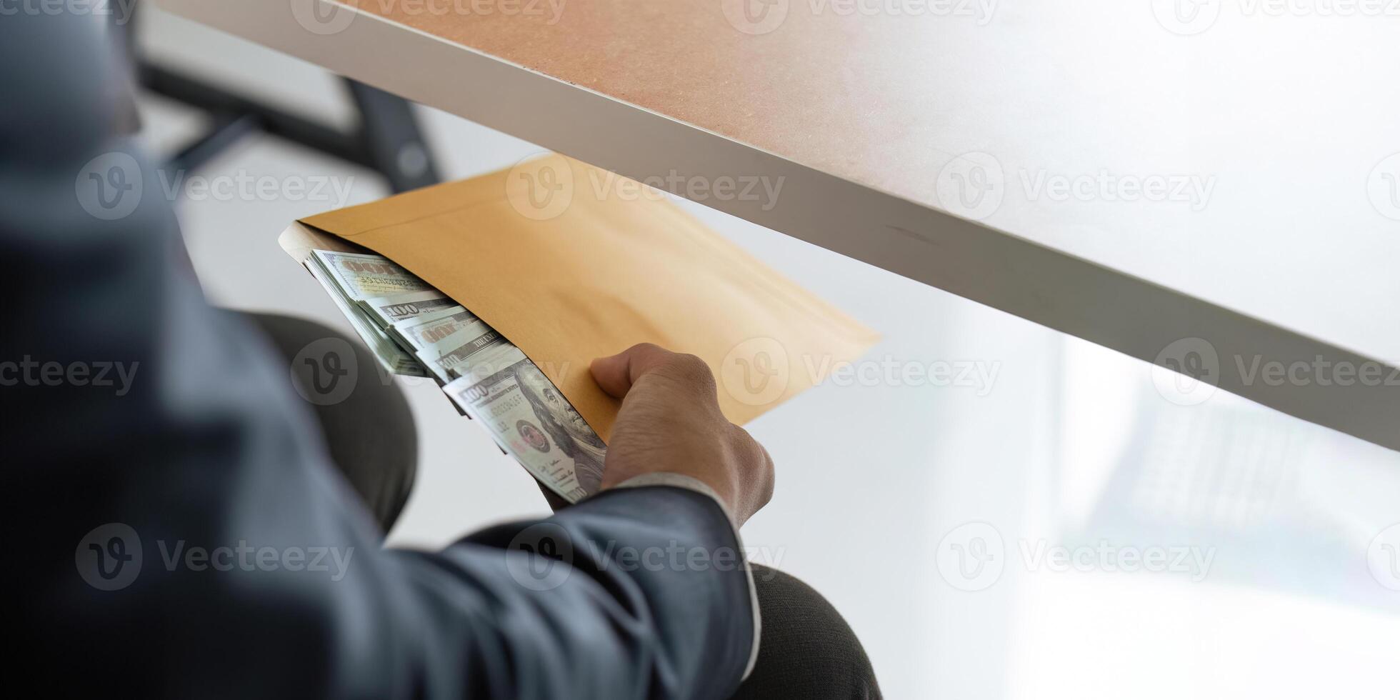Businessman briefcase document envelope with dollar banknotes while money passes under a table. business accept illegal secret agreement money. concept corruption, bribery, crime and embezzle photo