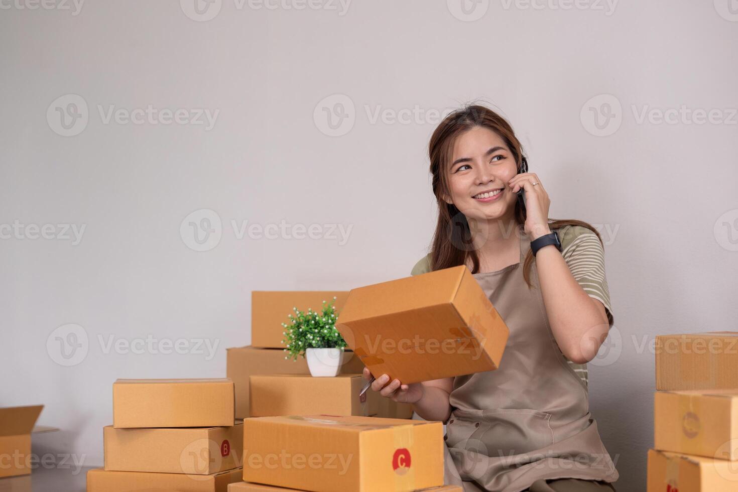 Asian woman holding parcel box and check order from cellphone. Online selling and online shopping concept photo