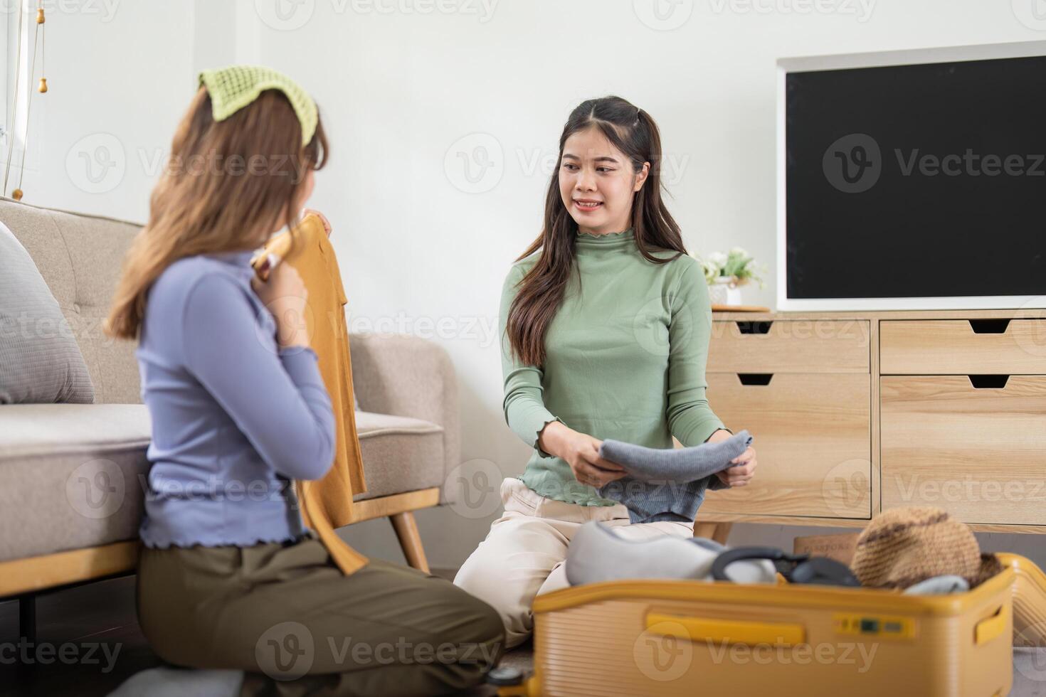 Asian woman prepare to pack clothes travel places with her friends. Asian beautiful two women friend pack things in your travel bag for holidays for her vacation trip photo