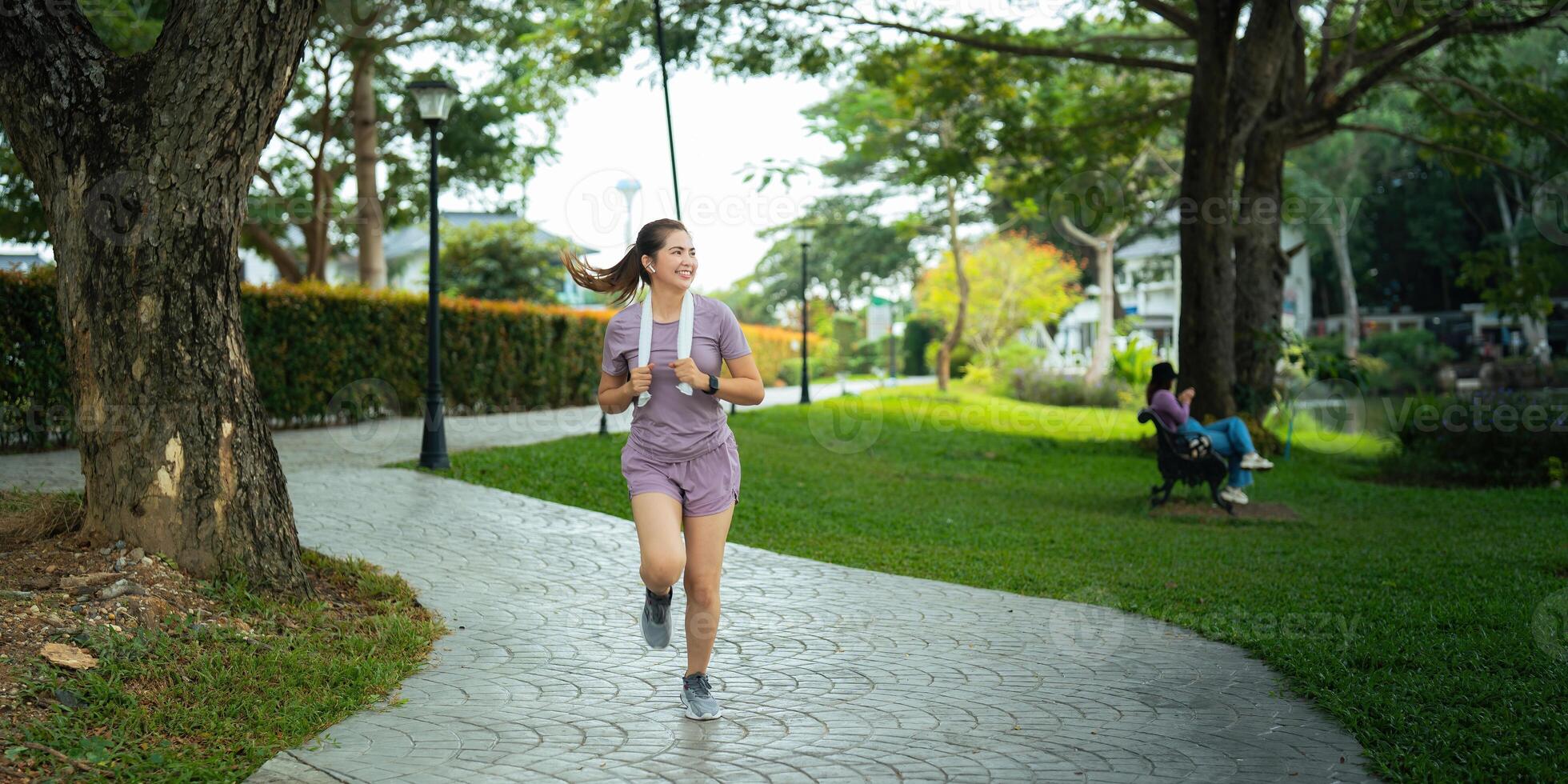 Jogging woman running in park on beautiful day off. Sport fitness model of asian ethnicity training outdoor for marathon photo