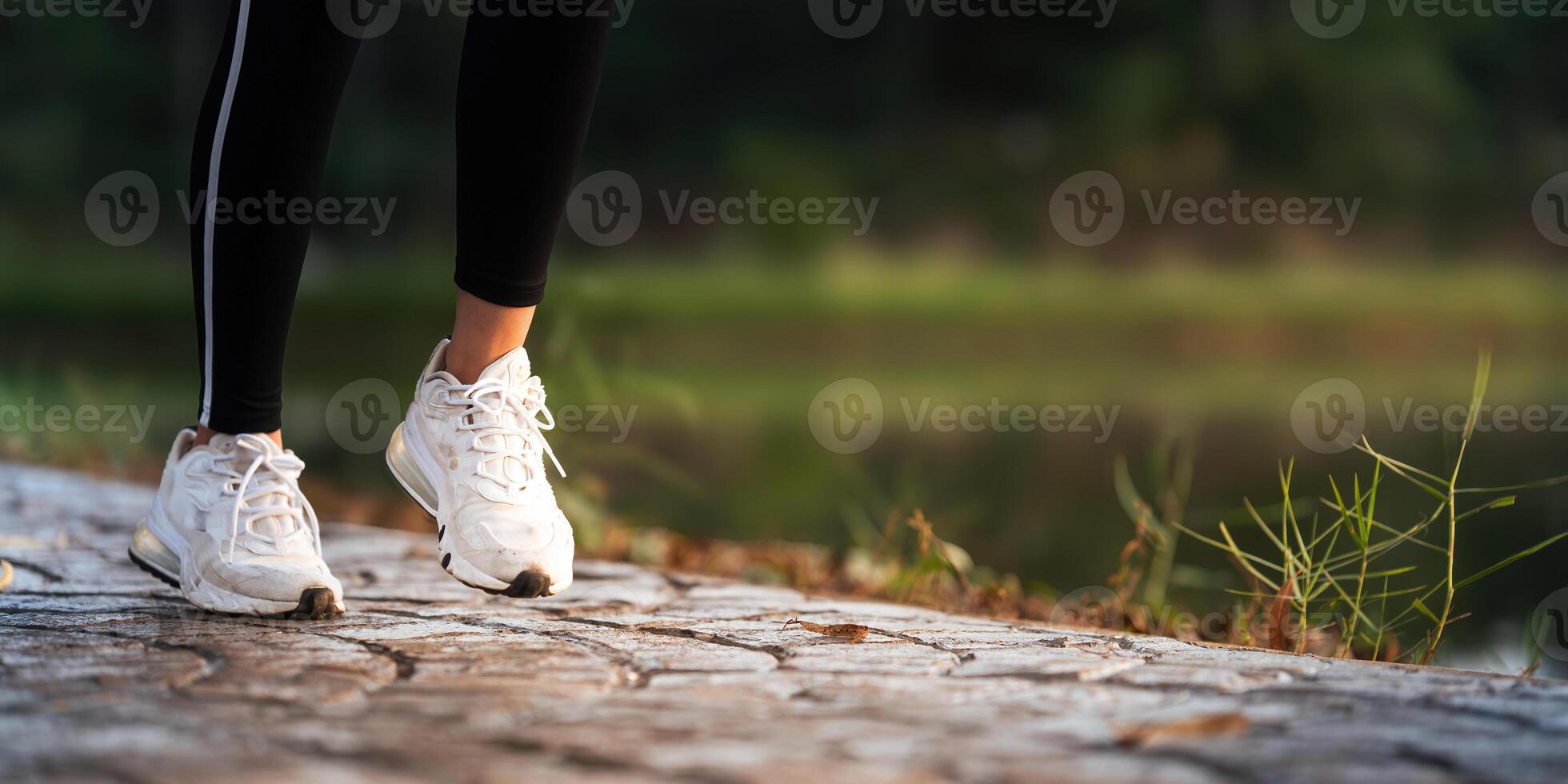 Jogging woman running in park on beautiful day off. Sport fitness model of asian ethnicity training outdoor for marathon photo