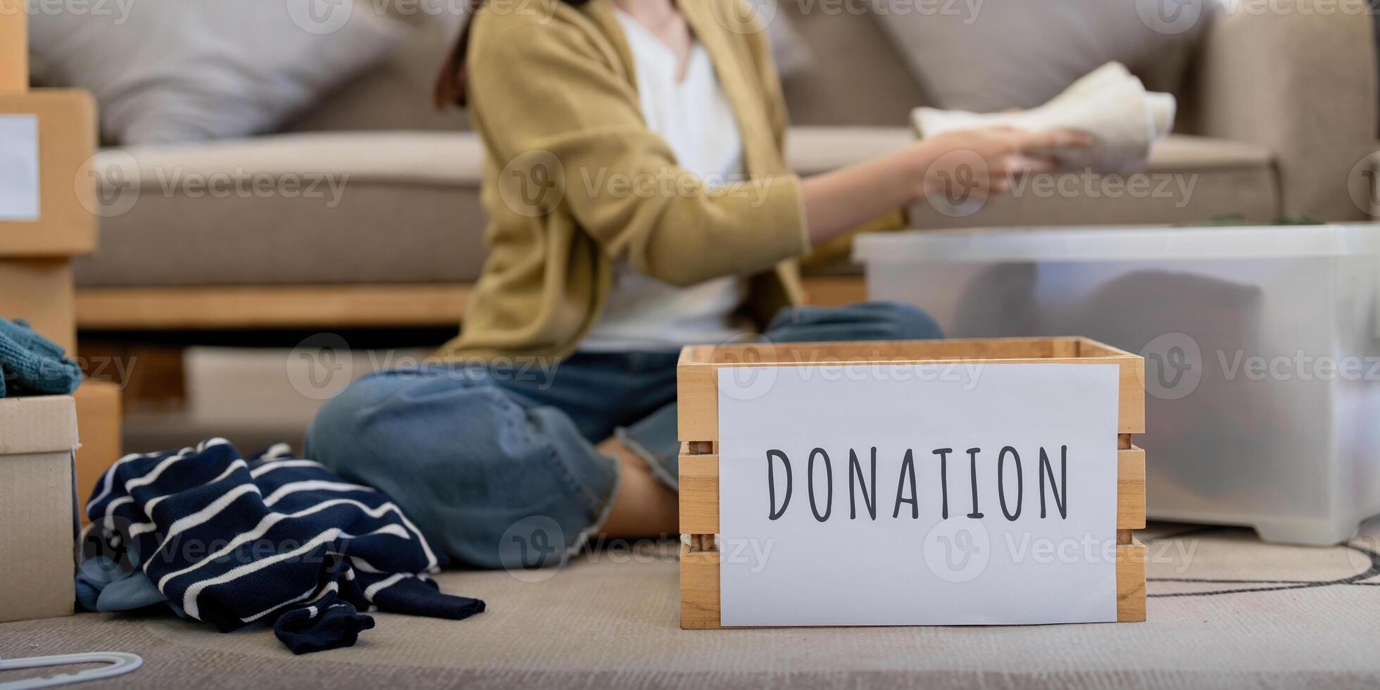 Donation, asian young woman sitting pack object at home, putting on stuff into donate box with second hand clothes, charity helping and needy people. Reuse recycle photo