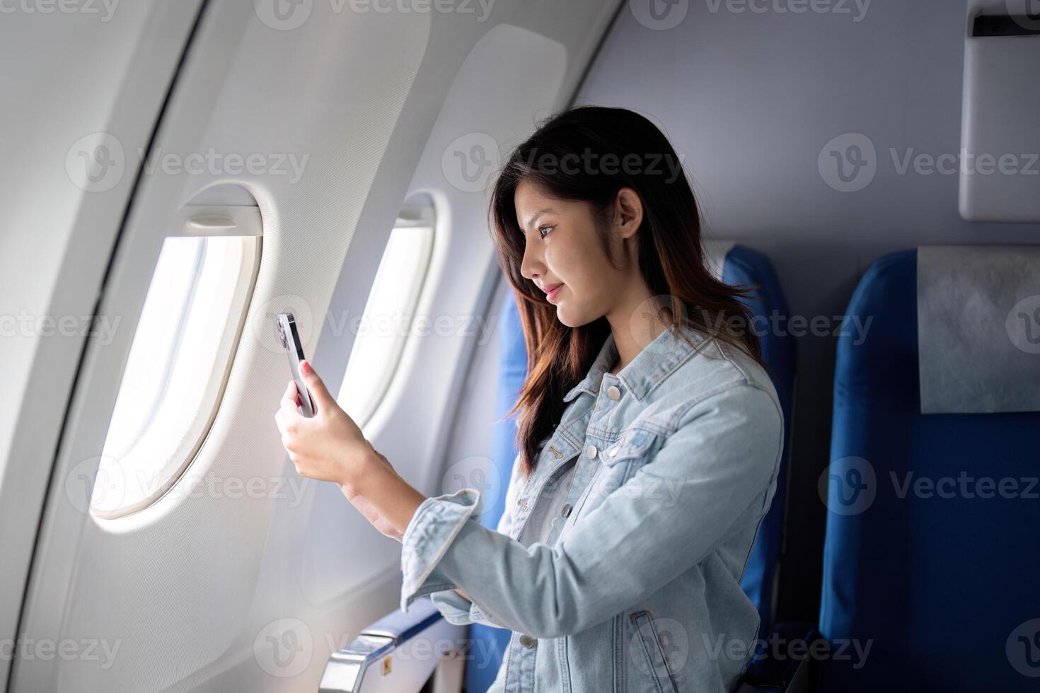 Asian woman taking photo out airplane window during flight