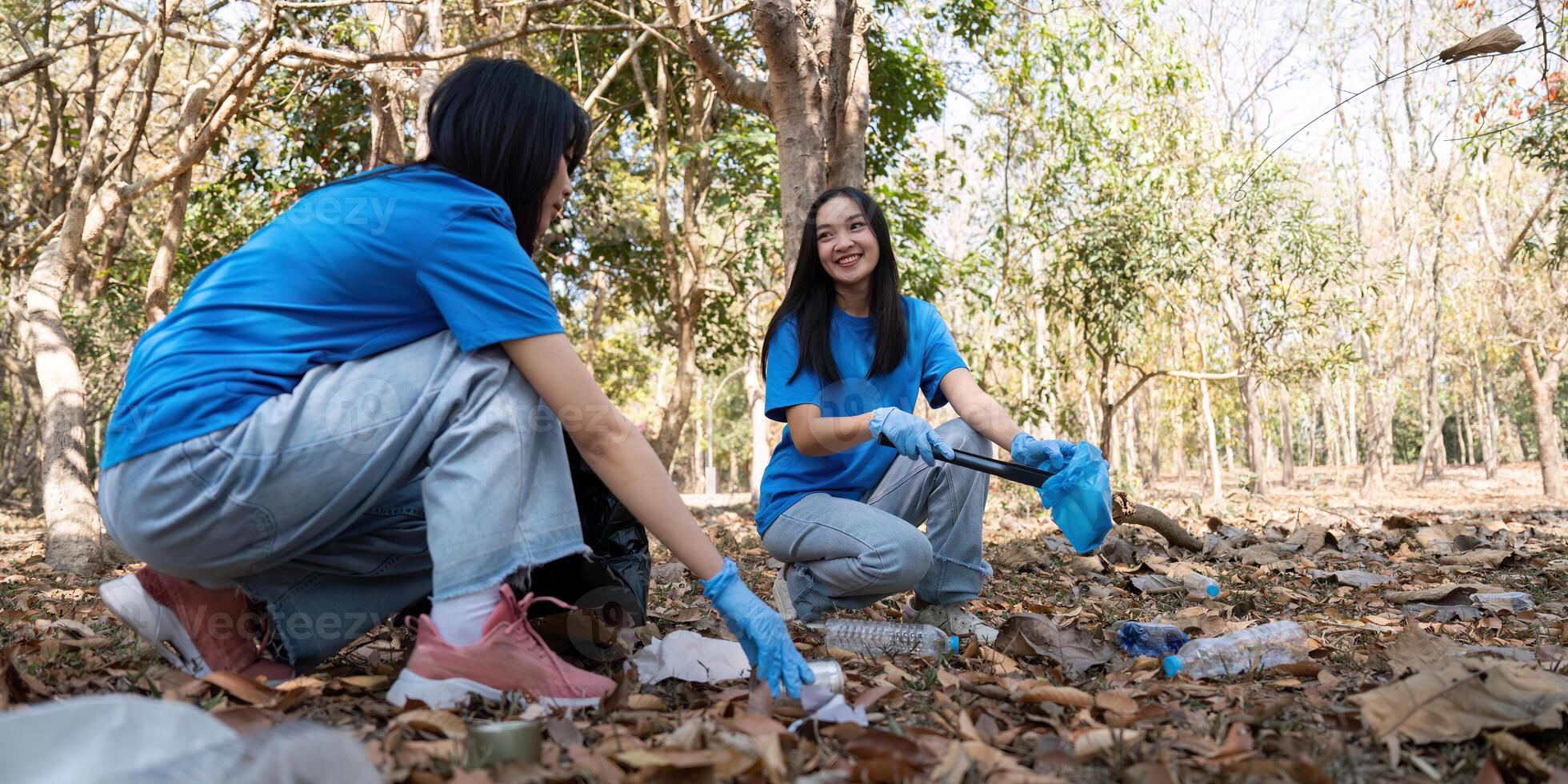 Female volunteer picking up litter in forest. Concept of teamwork, environment, and community service photo