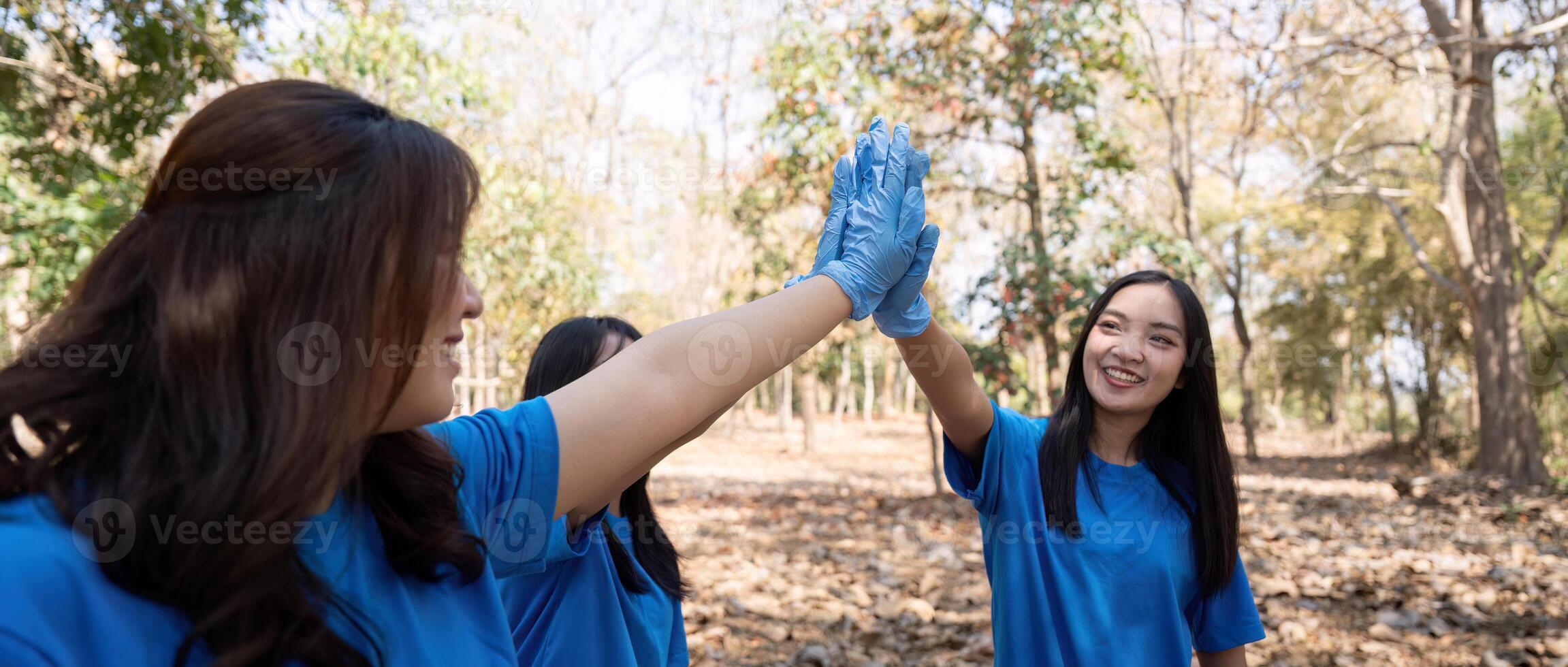 Female volunteer high fiving in forest. Concept of teamwork, unity, and environmental service photo