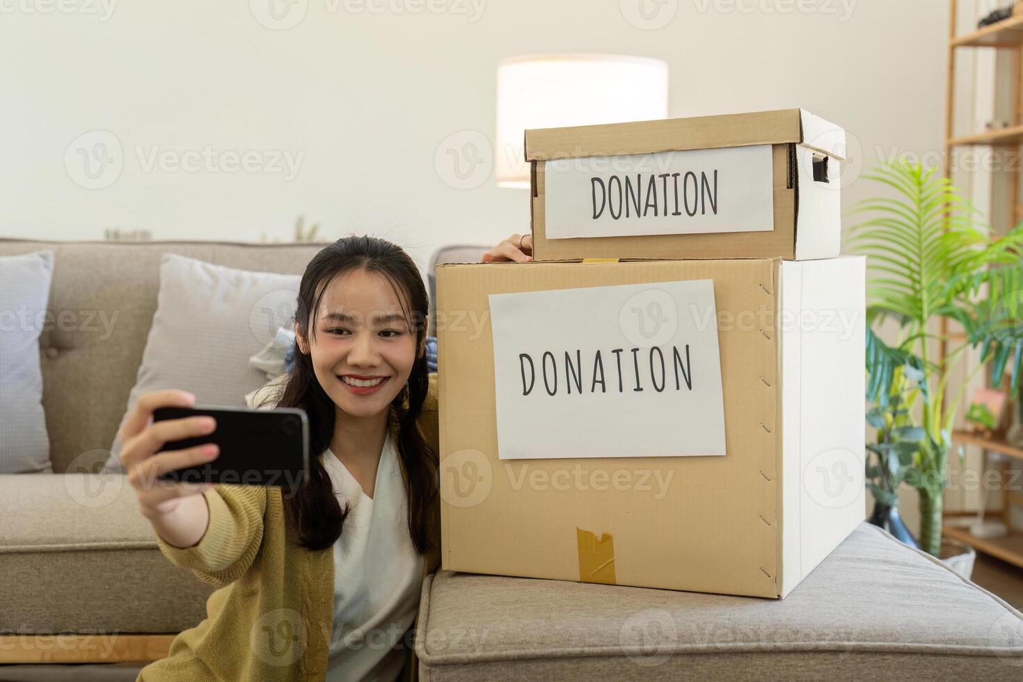 Woman taking selfie with donation boxes at home. Concept of charity, volunteering, and community support photo