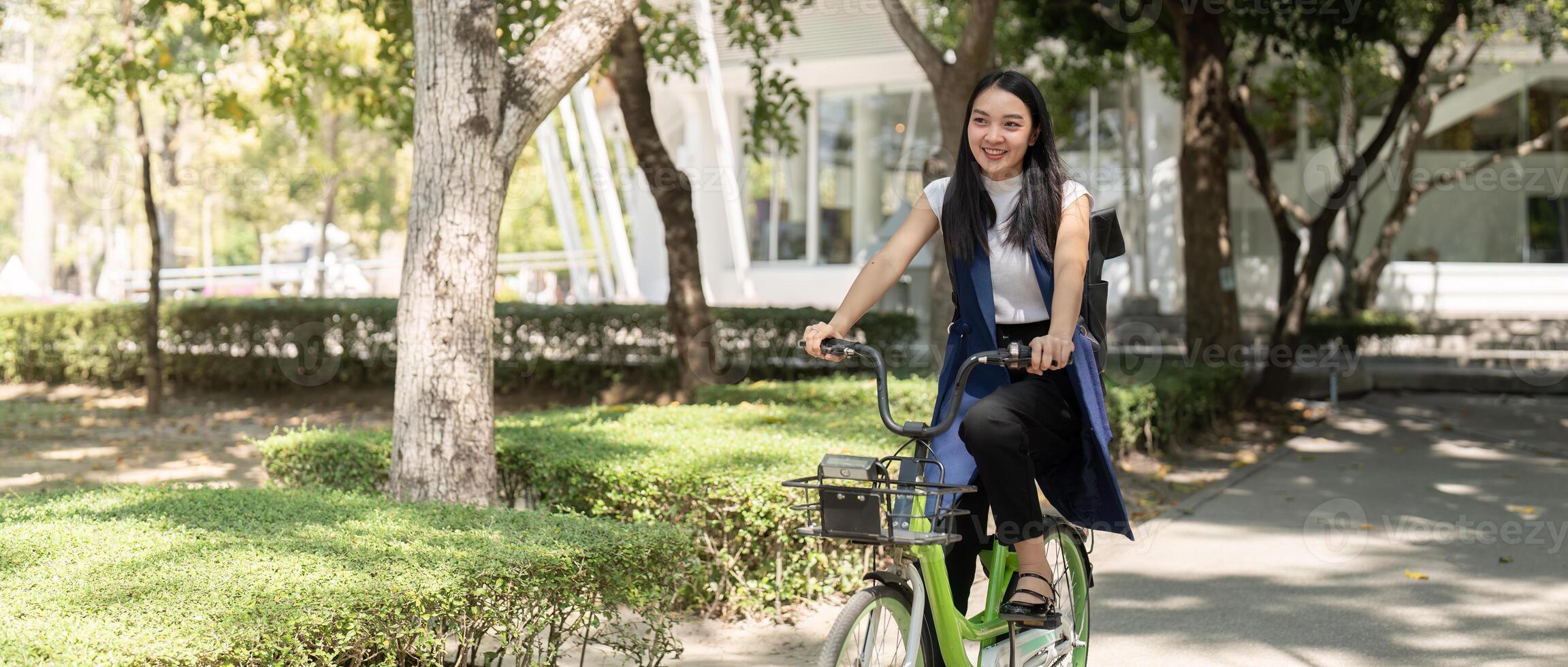Smiling Asian woman cycling in park. Concept of eco friendly transportation photo