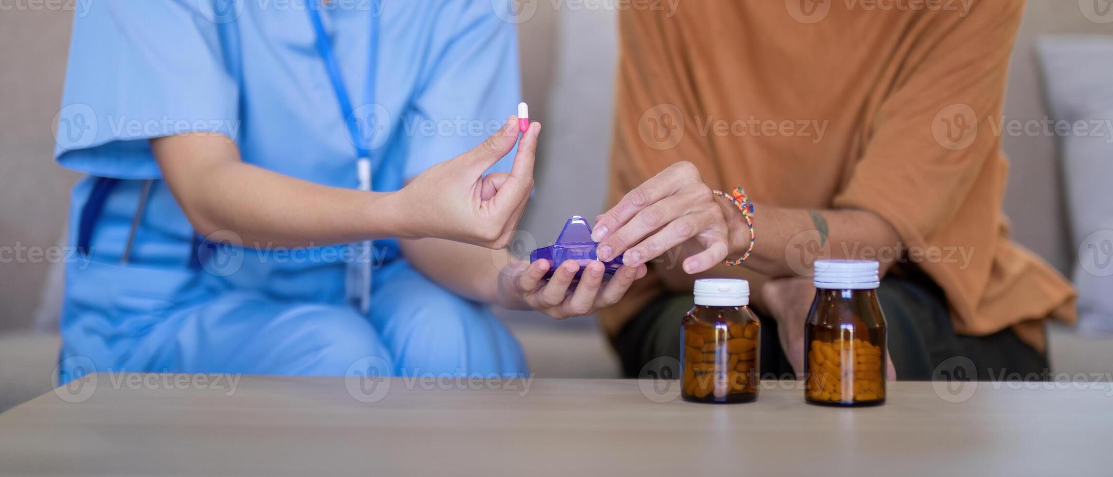 Close up of Asian caregiver demonstrating medication to elderly woman at home. Concept of elderly care and medication management photo
