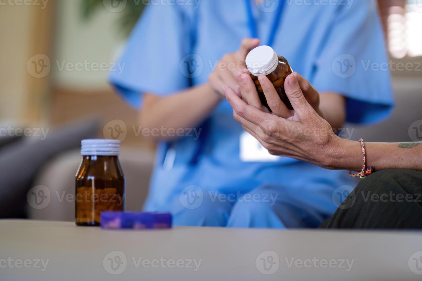 Close up of Asian caregiver assisting elderly woman with medication at home. Concept of elderly care and medical assistance photo