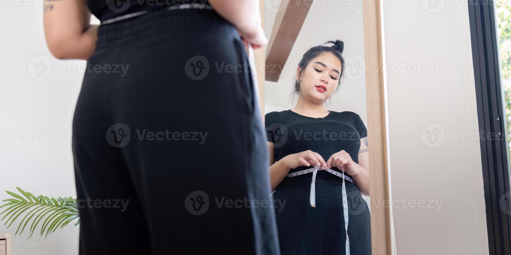 Young woman measuring waist in front of mirror. Concept of fitness and body positivity photo
