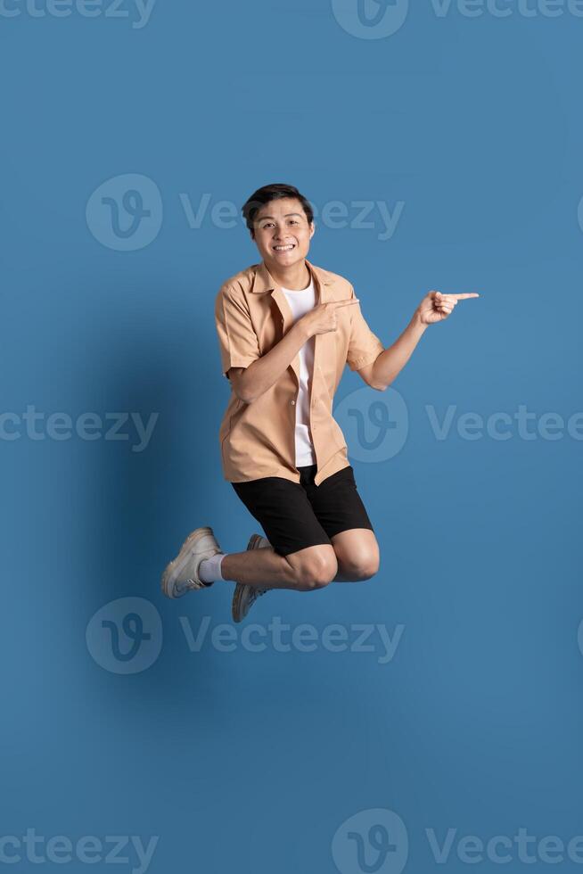 Portrait of Asian man posing on blue background, traveling in summer photo
