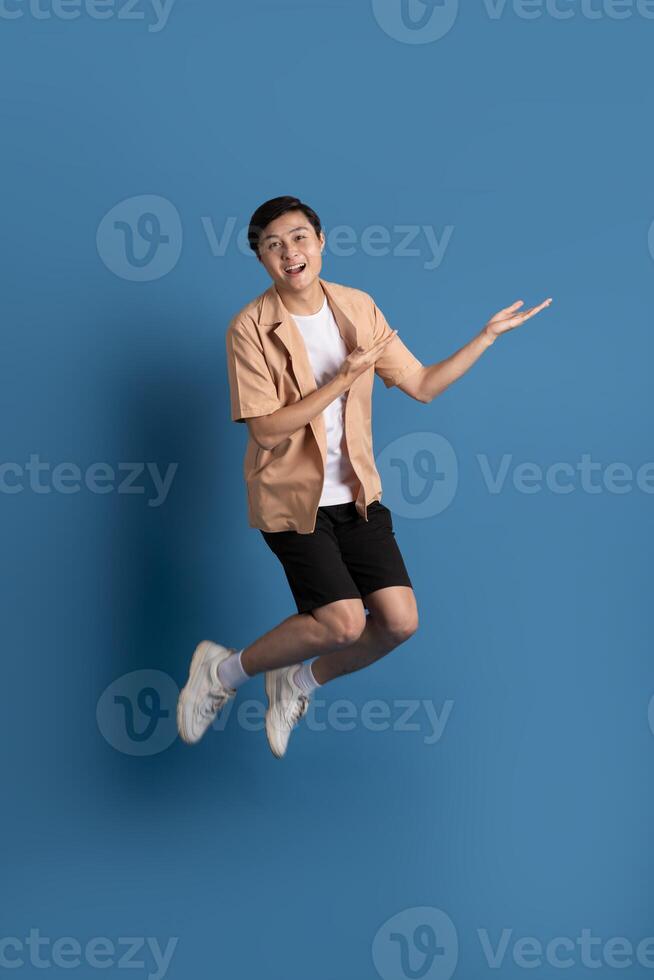 Portrait of Asian man posing on blue background, traveling in summer photo