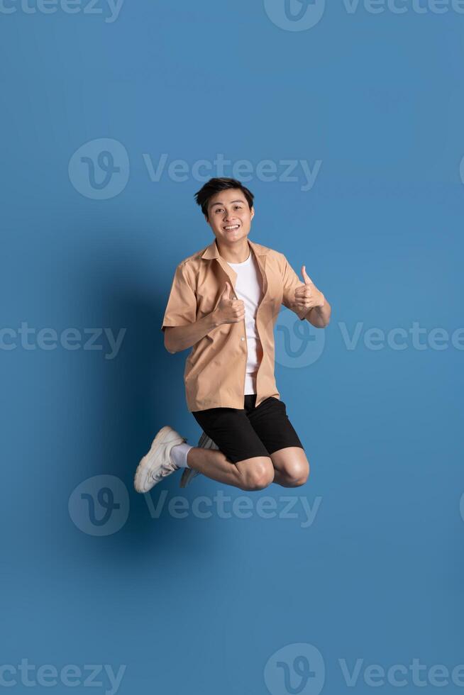 Portrait of Asian man posing on blue background, traveling in summer photo