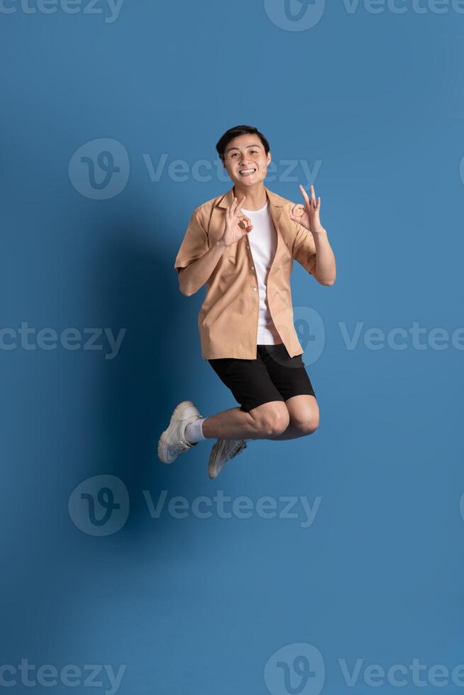 Portrait of Asian man posing on blue background, traveling in summer photo