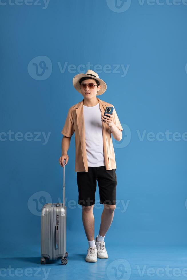 Portrait of Asian man posing on blue background, traveling in summer photo