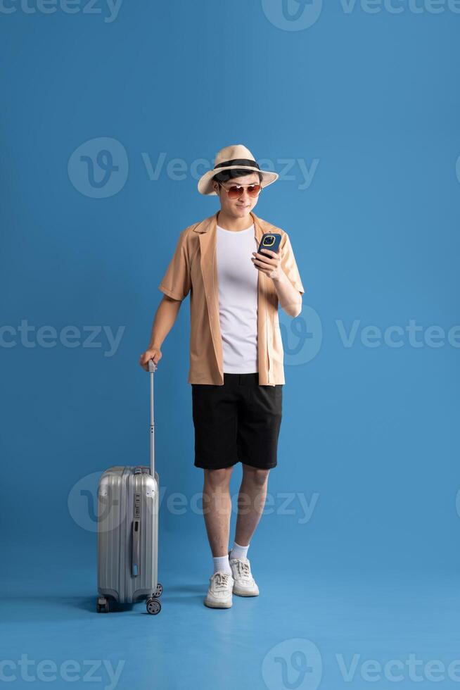Portrait of Asian man posing on blue background, traveling in summer photo