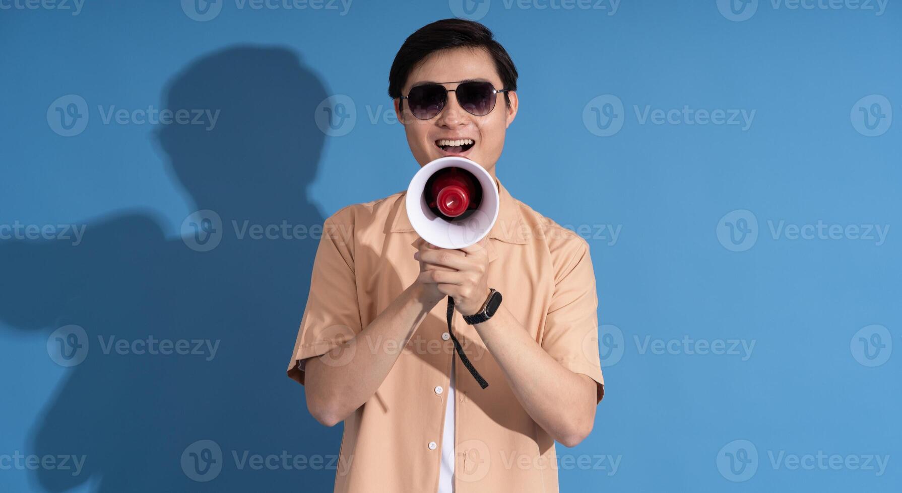 Portrait of Asian man posing on blue background, traveling in summer photo