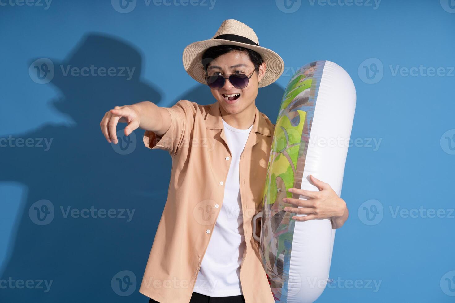 Portrait of Asian man posing on blue background, traveling in summer photo