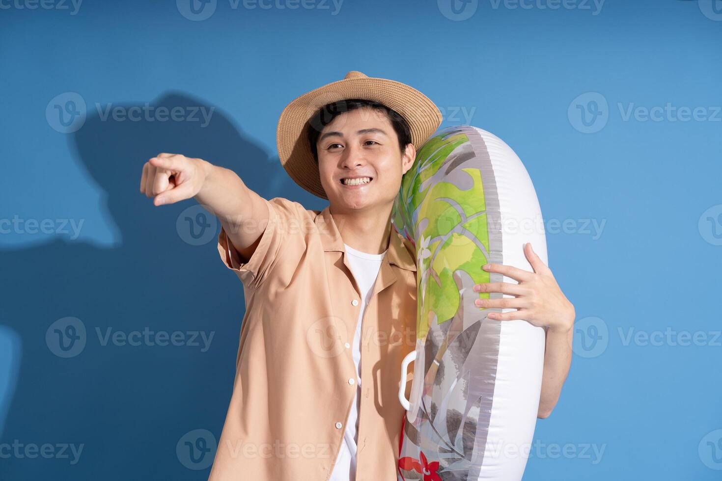 Portrait of Asian man posing on blue background, traveling in summer photo