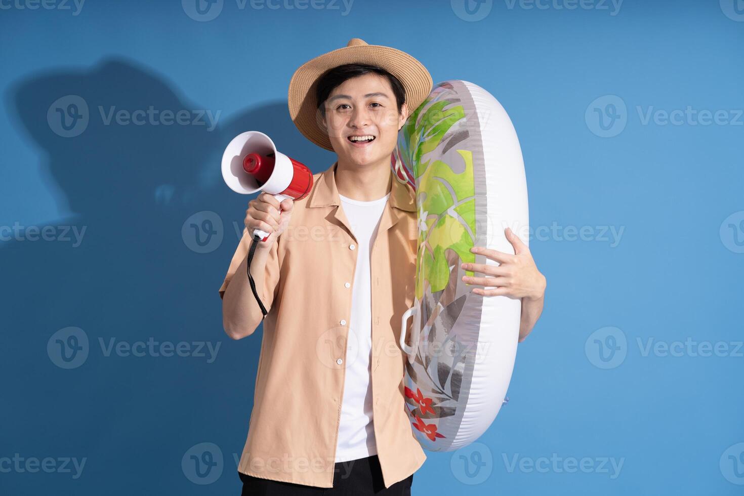 Portrait of Asian man posing on blue background, traveling in summer photo