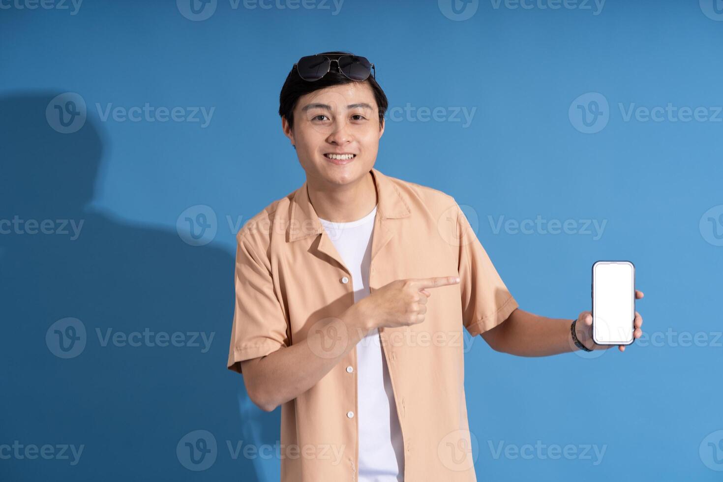 Portrait of Asian man posing on blue background, traveling in summer photo
