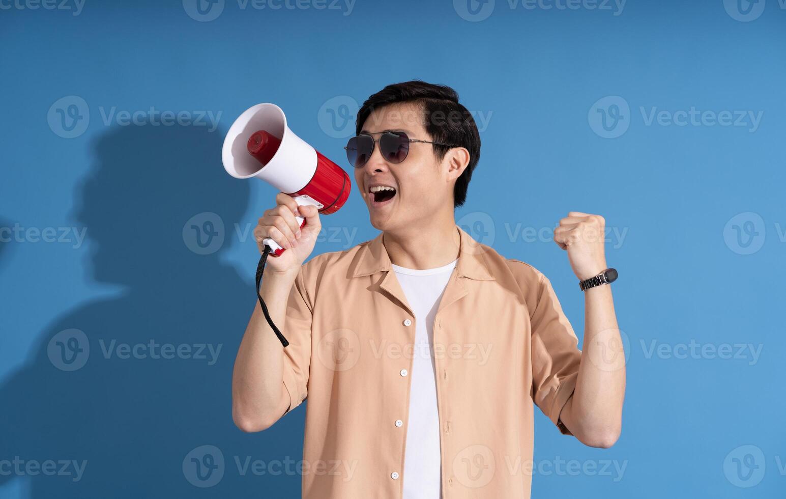 Portrait of Asian man posing on blue background, traveling in summer photo