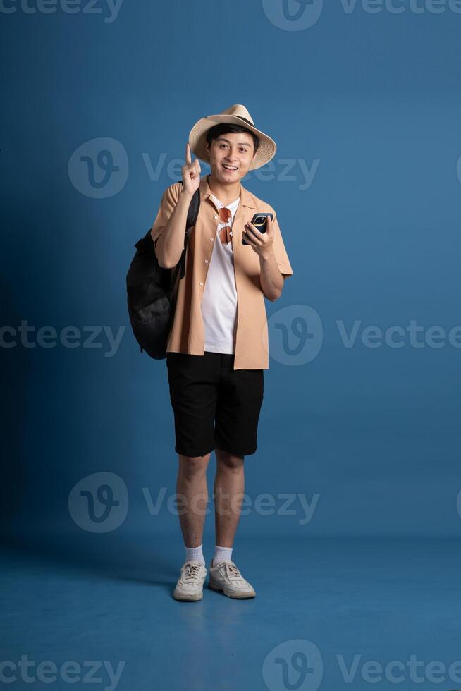 Portrait of Asian man posing on blue background, traveling in summer photo