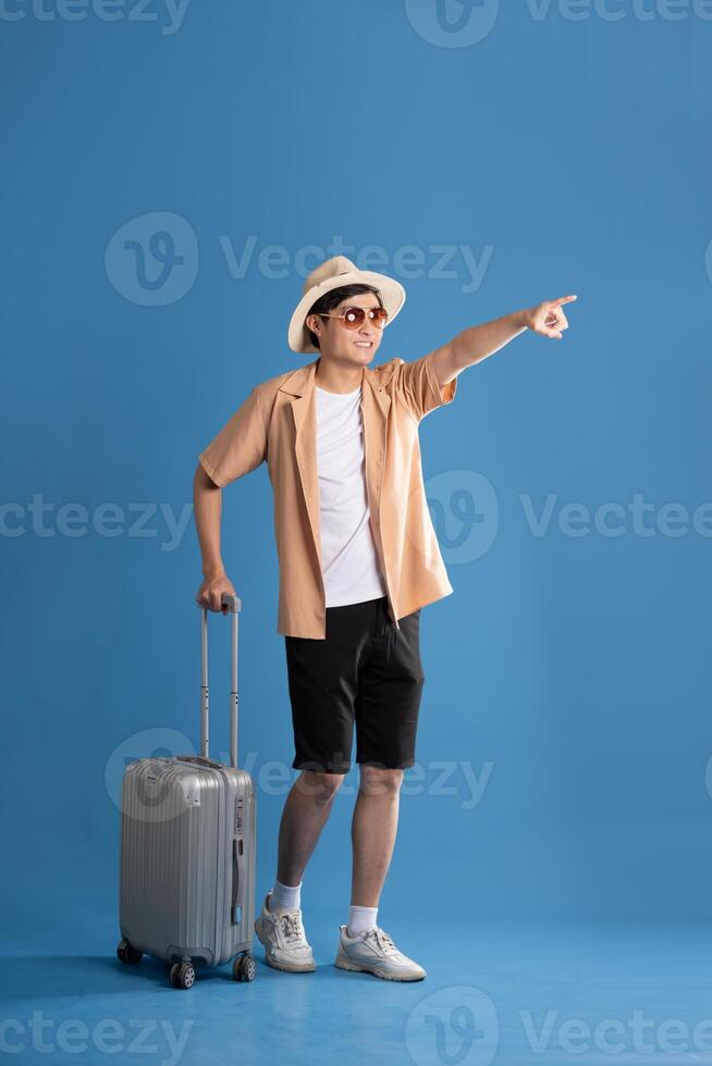 Portrait of Asian man posing on blue background, traveling in summer photo