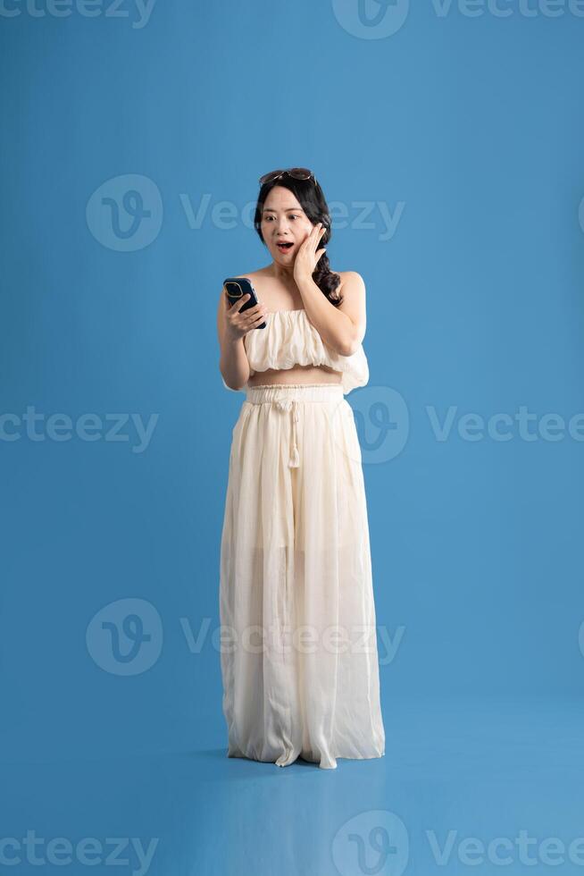 Portrait of asian girl posing on blue background, traveling in summer photo