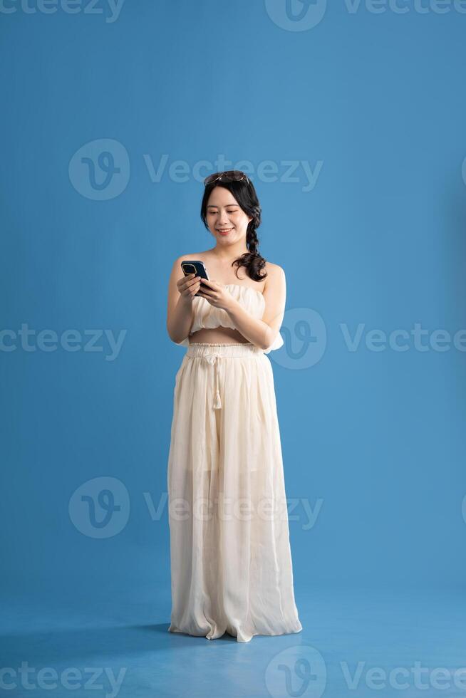 Portrait of asian girl posing on blue background, traveling in summer photo