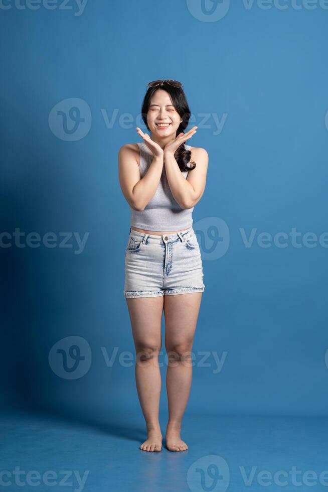 Portrait of asian girl posing on blue background, traveling in summer photo