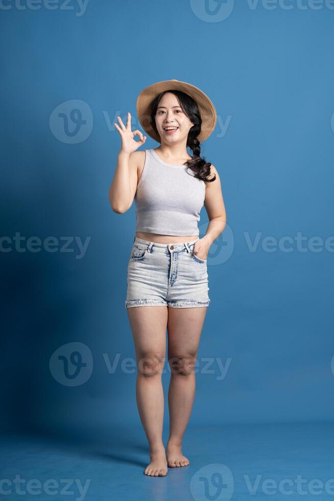 Portrait of asian girl posing on blue background, traveling in summer photo