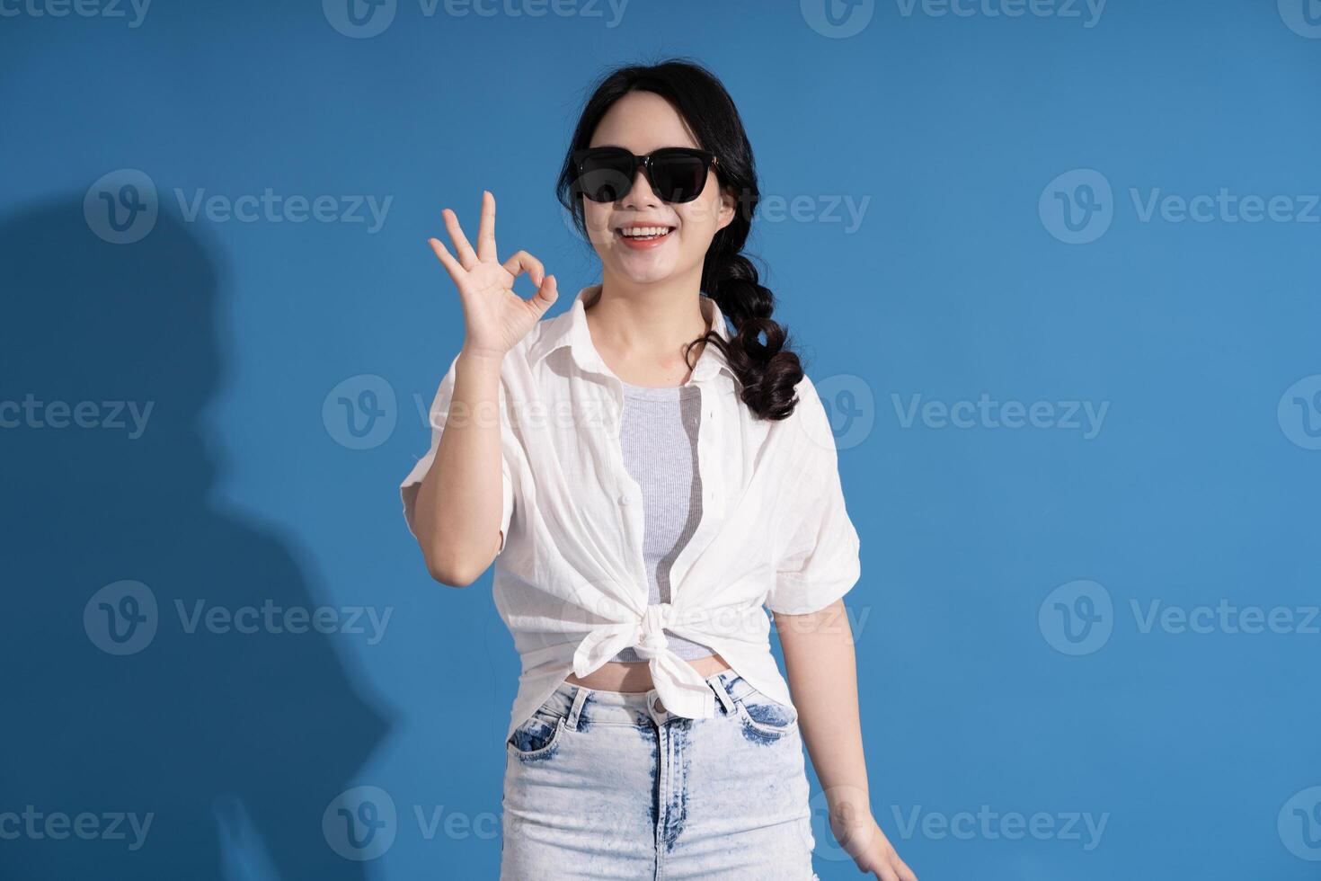 Portrait of asian girl posing on blue background, traveling in summer photo