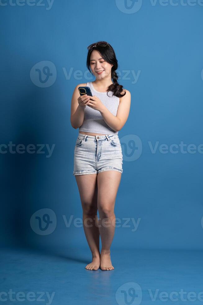 Portrait of asian girl posing on blue background, traveling in summer photo