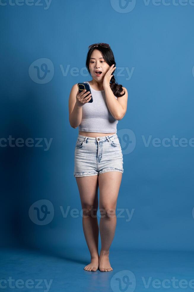 Portrait of asian girl posing on blue background, traveling in summer photo