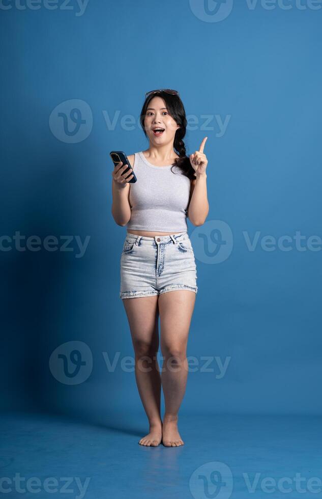 Portrait of asian girl posing on blue background, traveling in summer photo