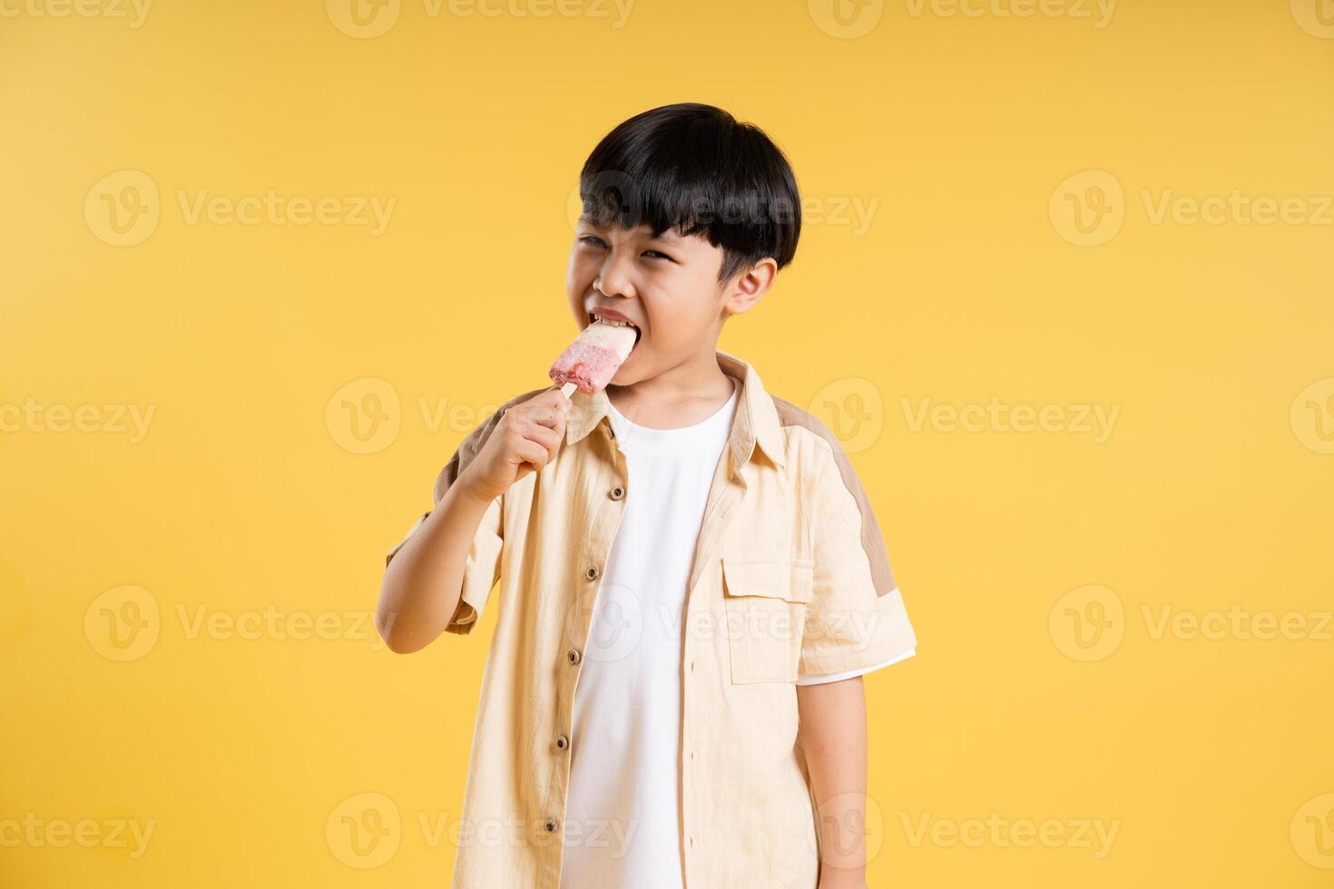 Portrait of adorable asian boy posing on yellow background photo