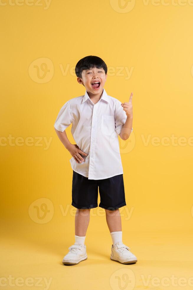 Portrait of adorable asian boy posing on yellow background photo