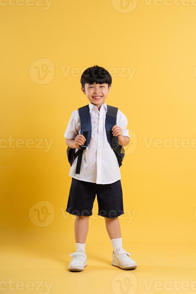 Portrait of adorable asian boy posing on yellow background photo