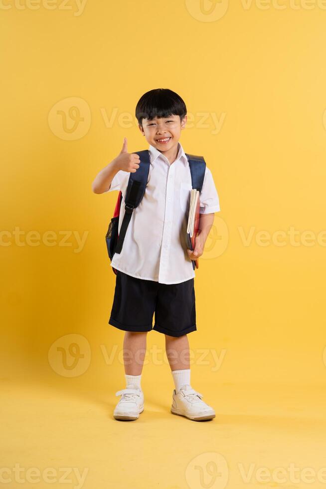 Portrait of adorable asian boy posing on yellow background photo