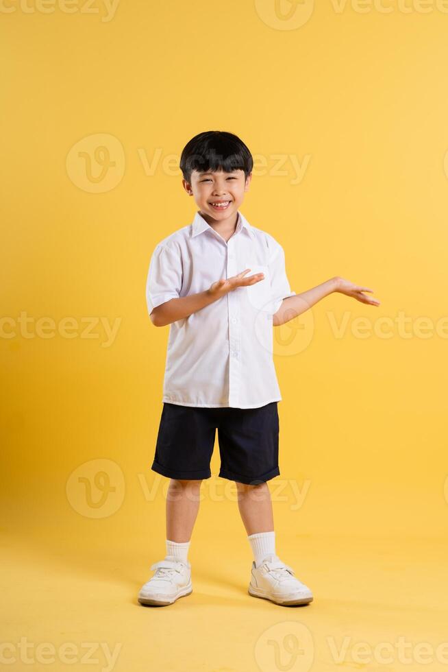 Portrait of adorable asian boy posing on yellow background photo