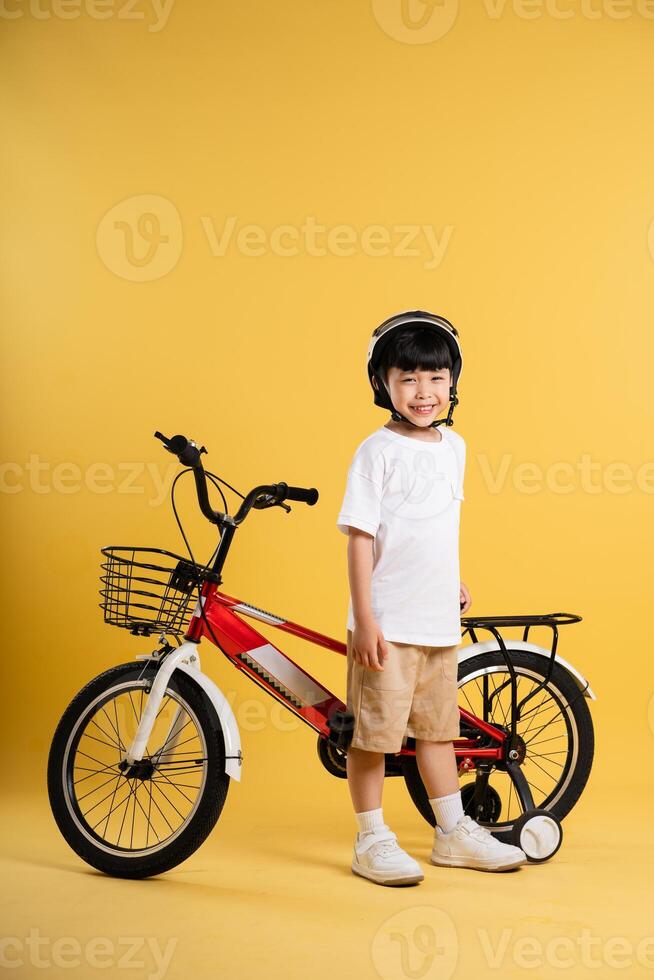 Portrait of adorable asian boy posing on yellow background photo